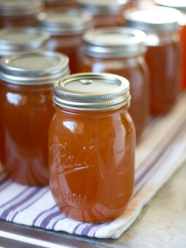 Row of mason jars filled with homemade beef bone broth on a shelf