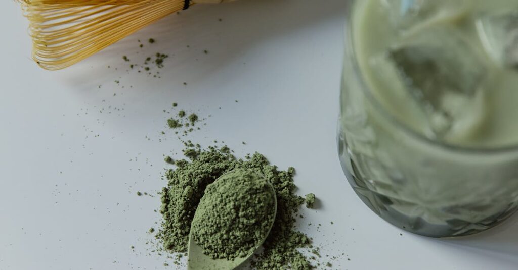 Top view of matcha latte with bamboo whisk and green tea powder.